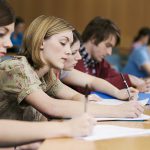 University students take notes in a lecture hall University students take notes in a lecture hall